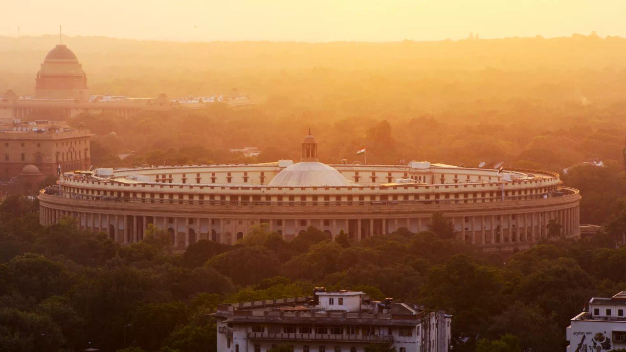 Parliament House in New Delhi at sunrise, with Rashtrapati Bhavan in the distance.